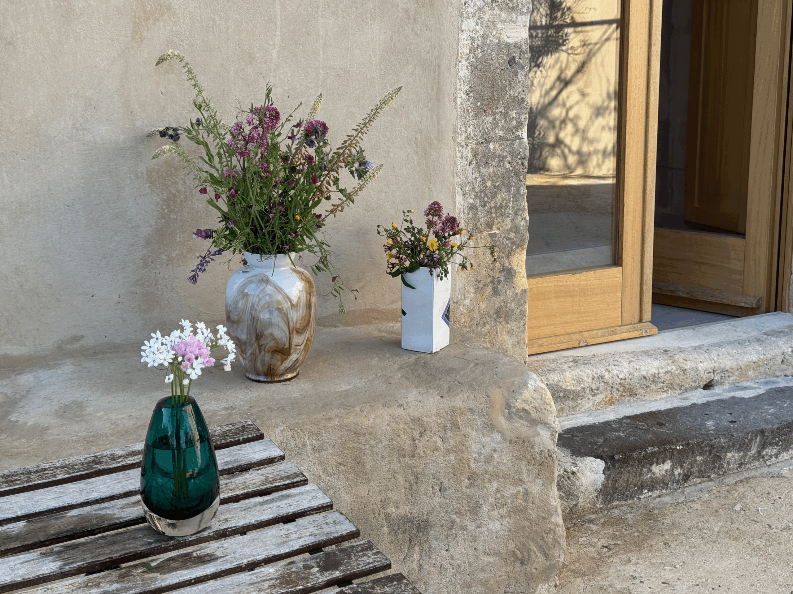 Three flower vases on Sicilian stone at dusk — quiet, understated